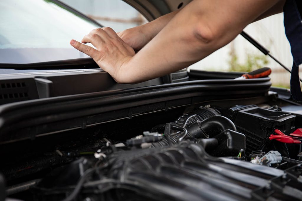 Mechanic working on car engine with focus on hands and engine components.